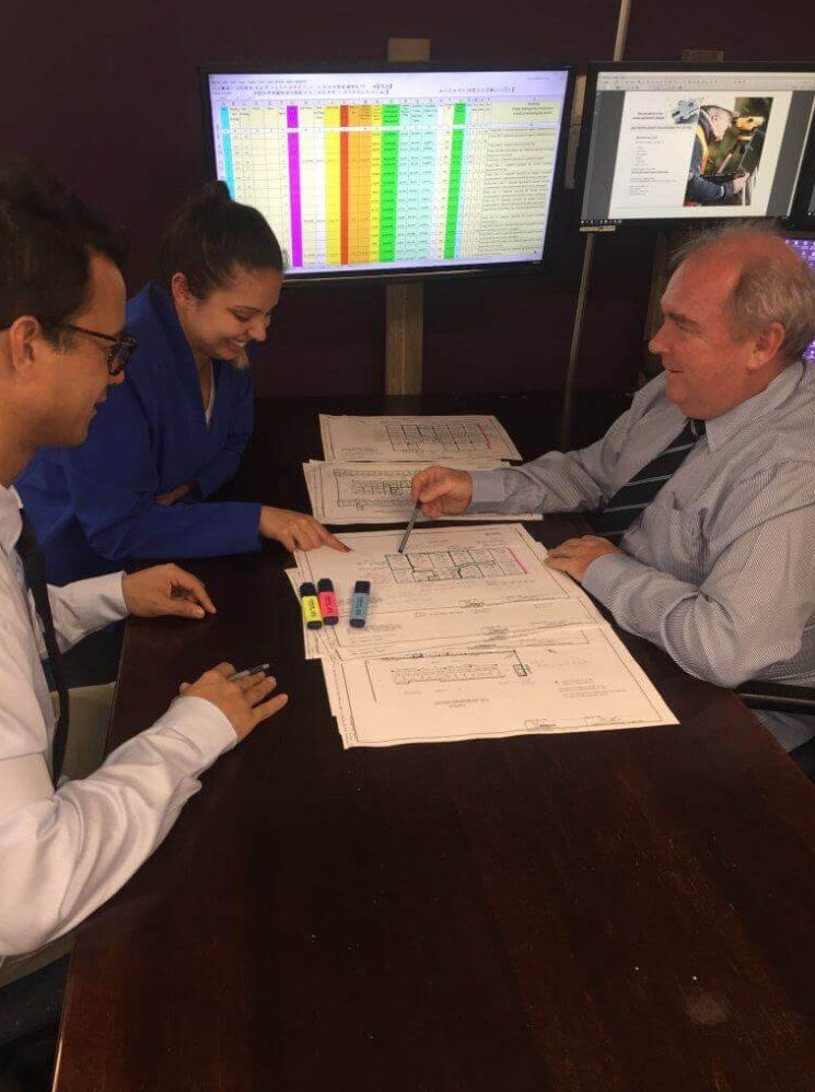 Strata valuers reviewing strata plan drawings and unit entitlement figures at a meeting table